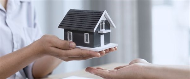 Handing Over Ownership. Woman holding small house to another person representing transition of ownership